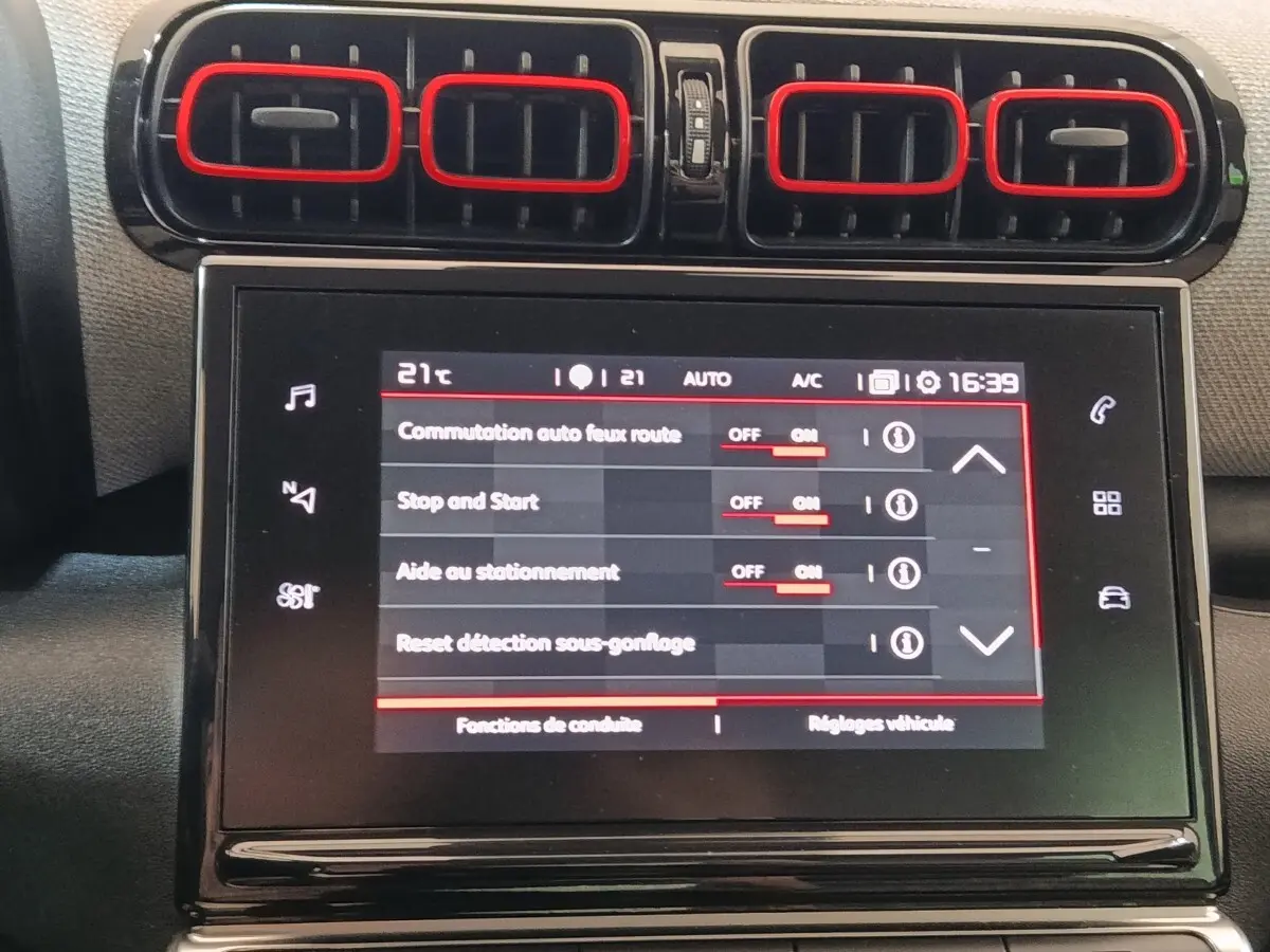 Gros plan sur l’écran tactile central et les aérateurs noirs avec contours rouges du tableau de bord beige du Citroën C3 Aircross.