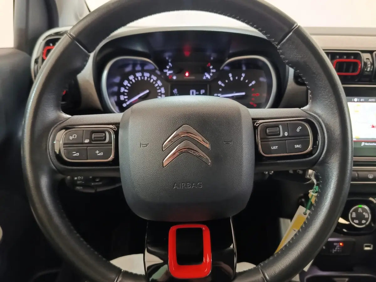 Vue rapprochée du volant noir avec logo Citroën et touches multifonctions rouges et noires du tableau de bord C3 Aircross.