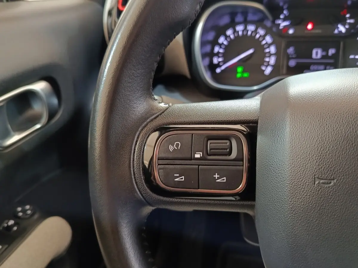 Gros plan sur le volant cuir noir de la Citroën C3 Aircross 2021 avec commandes audio intégrées côté gauche.