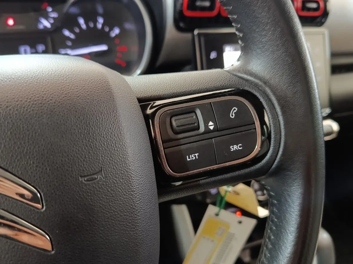 Gros plan sur le volant cuir noir de la Citroën C3 Aircross 2021, avec commandes audio et téléphone intégrées.
