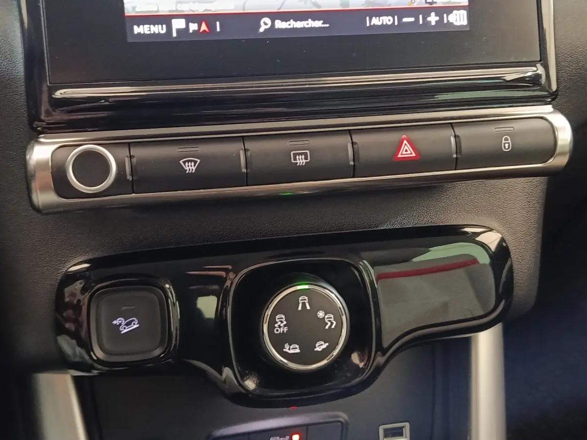 Gros plan sur la console centrale noire du Citroën C3 Aircross beige, avec commandes de traction et boutons de sécurité.