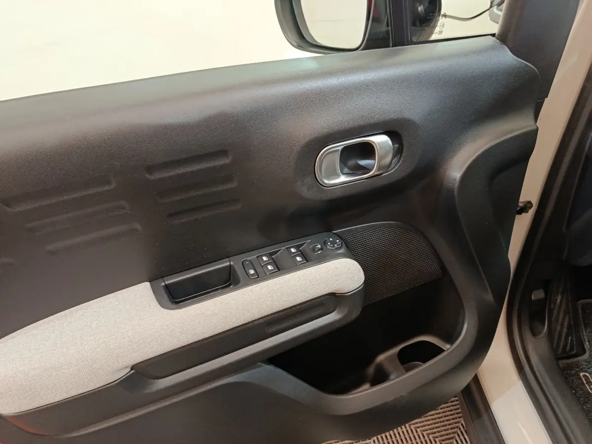 Vue rapprochée de la porte avant gauche beige du Citroën C3 Aircross avec commandes de vitres et poignée argentée.