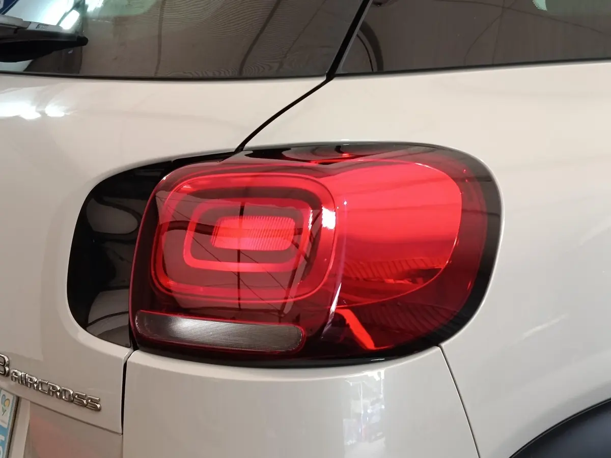 Gros plan sur le feu arrière droit rouge et la carrosserie beige d'une Citroën C3 Aircross 2021.