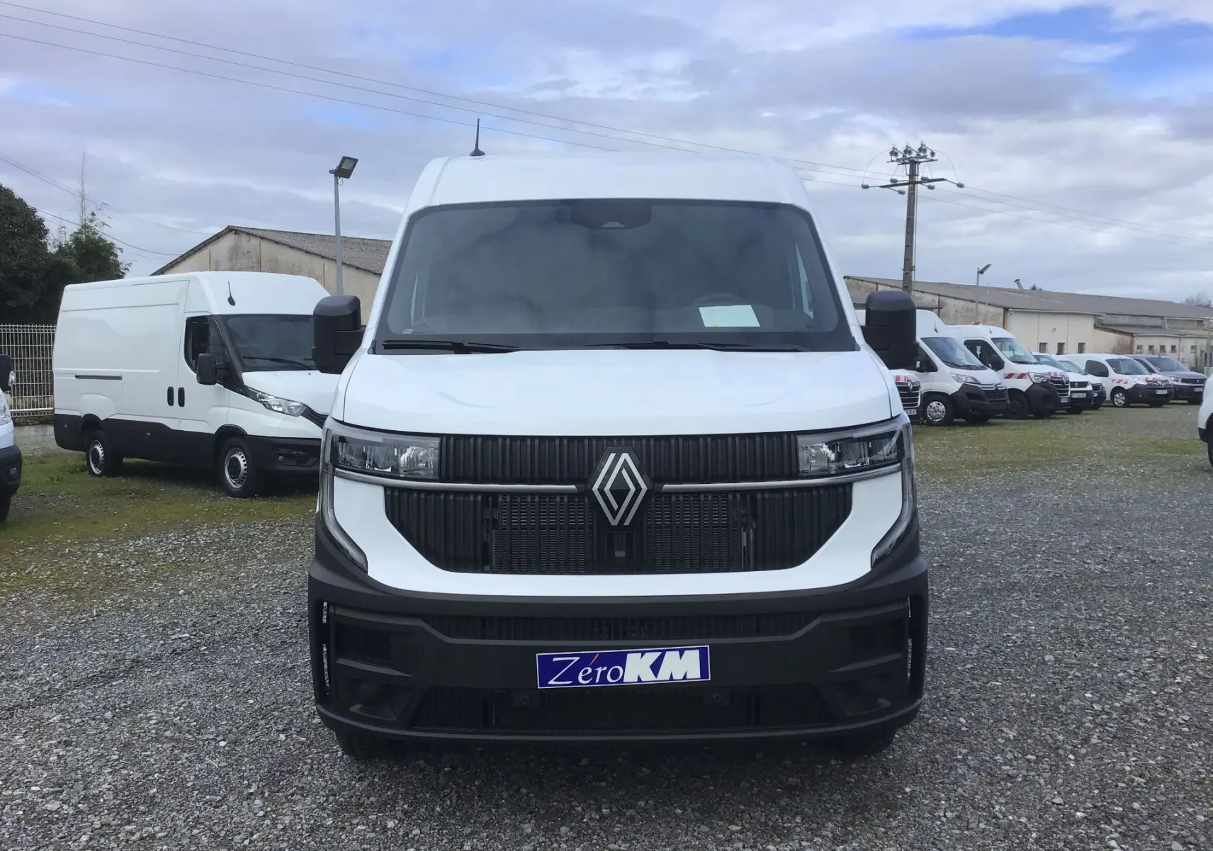 Vue frontale d’un Renault Master blanc 2026 avec calandre noire et logo Renault bien visible, sur un parking extérieur.