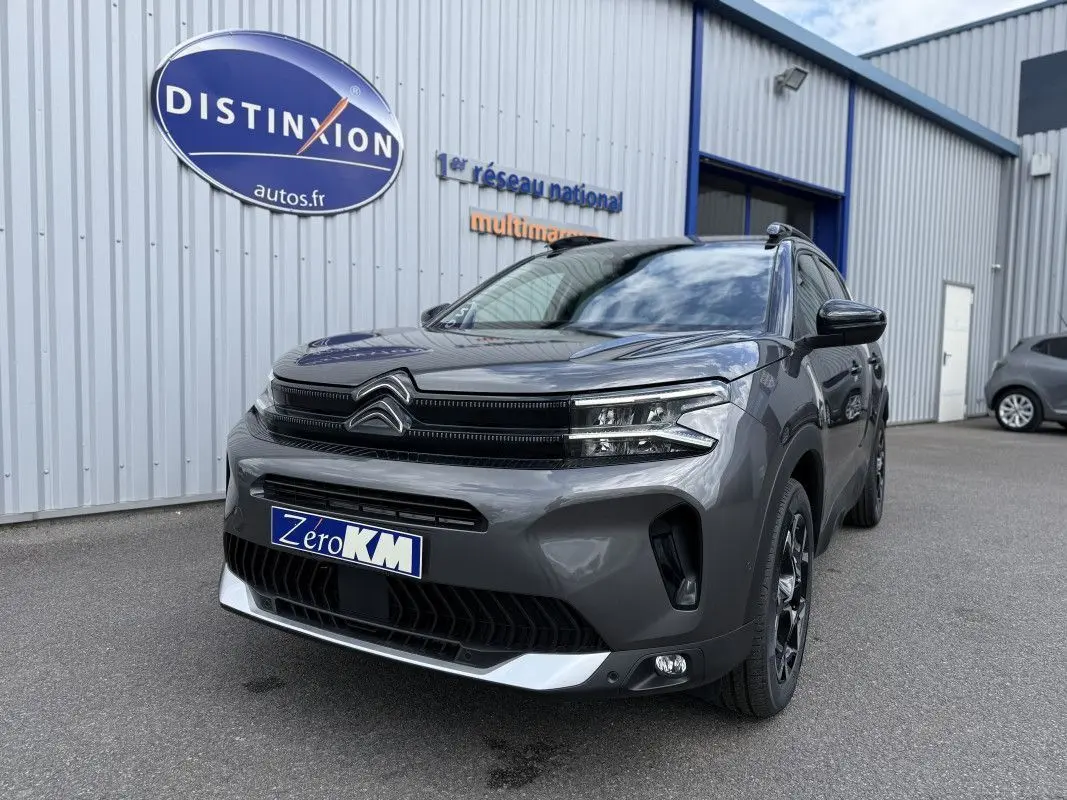 Vue 3/4 avant droit d'un Citroën C5 Aircross 2025 gris platinium métallisé avec calandre noire et jantes noires.