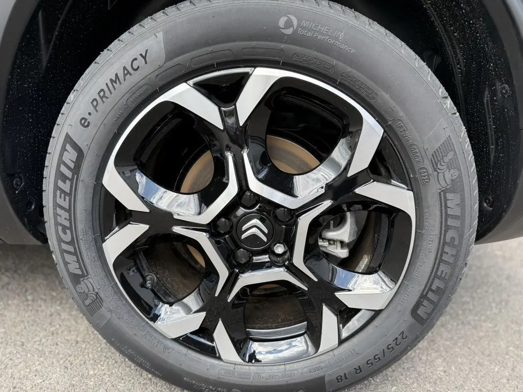 Gros plan sur la jante noire et argentée du Citroën C5 Aircross gris platinium, mettant en valeur le logo Citroën central.