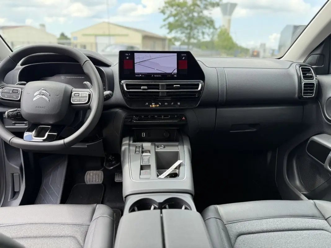 Vue intérieure avant du Citroën C5 Aircross 2025, tableau de bord noir avec écran tactile central et volant multifonction.
