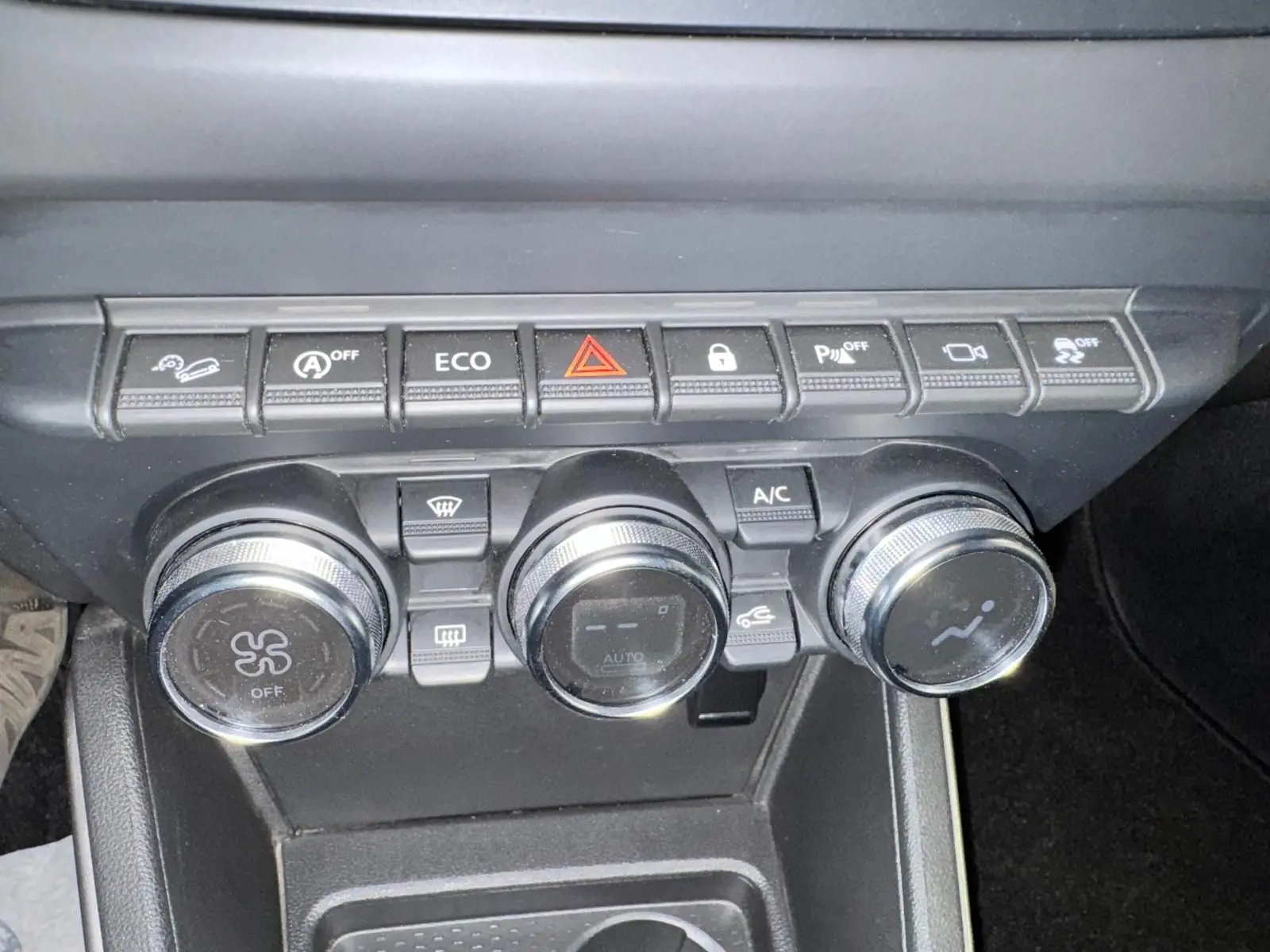 Gros plan sur la console centrale du Dacia Duster 2020, montrant les commandes de climatisation et les boutons de fonction.