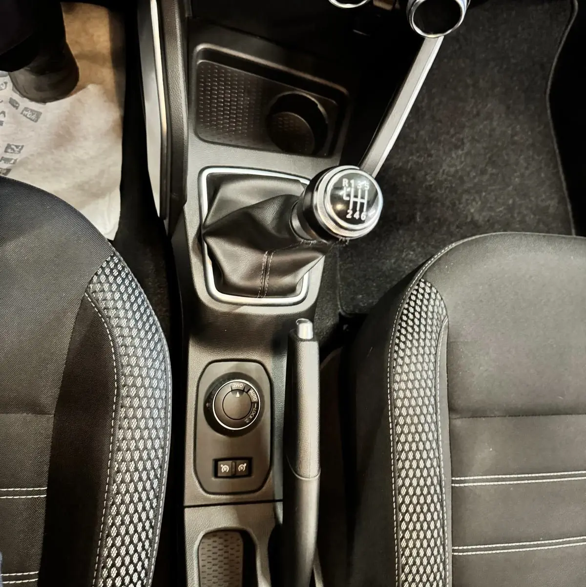 Vue plongeante sur la console centrale du Dacia Duster 2020, montrant levier de vitesse manuel et sièges noirs à motifs.