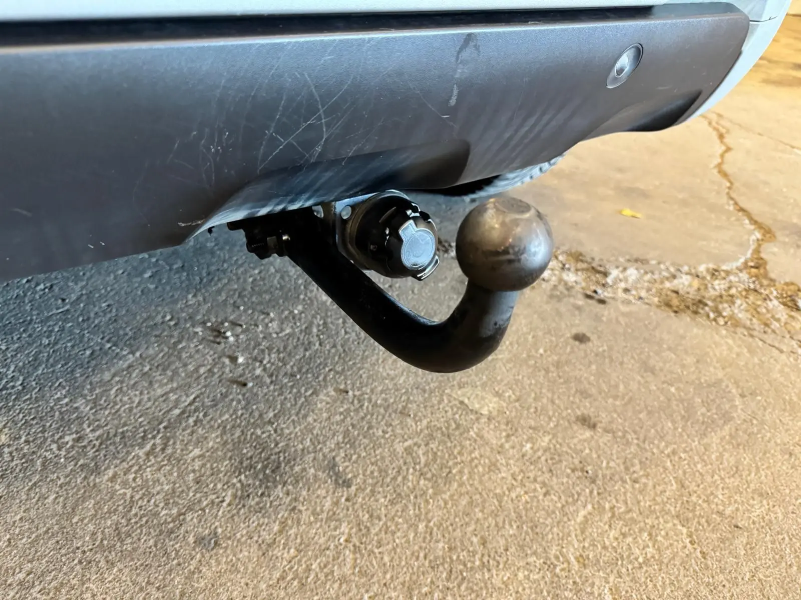 Gros plan sur l'attelage noir fixé sous le pare-chocs arrière gris du Dacia Duster 2020.
