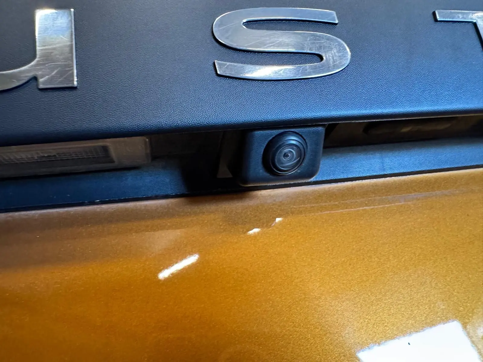 Gros plan sur la caméra de recul intégrée sous le logo Dacia sur la porte arrière orange du Duster 2020.