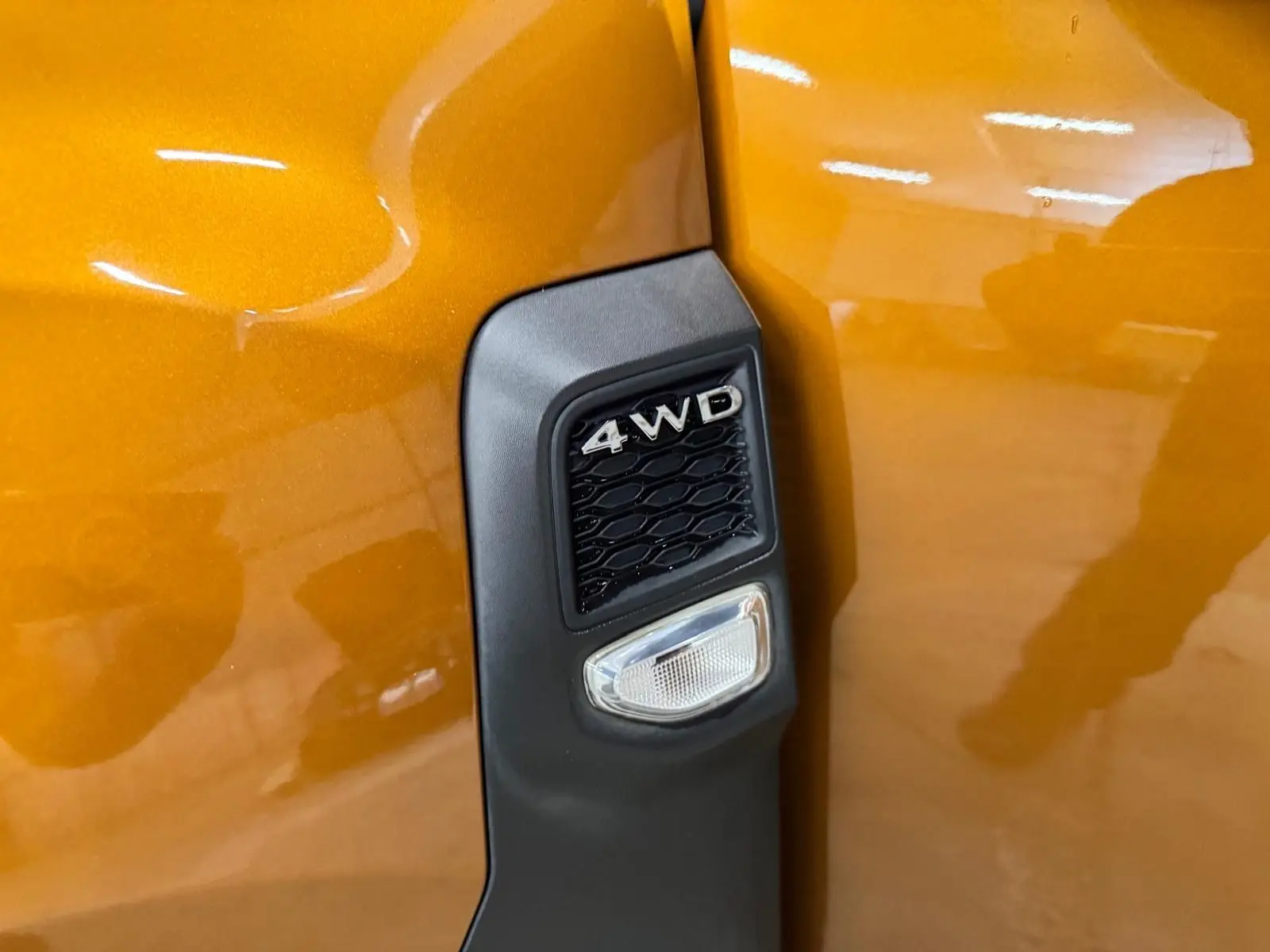Détail de l'aile avant droite orange du Dacia Duster 2020 avec badge 4WD noir et clignotant intégré.