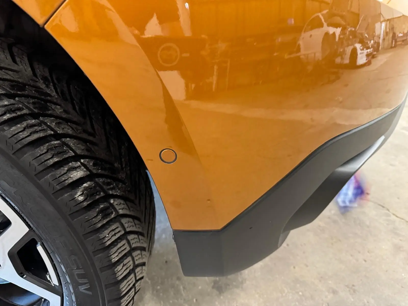 Détail de l’aile arrière droite orange du Dacia Duster 2020 avec roue et pare-chocs noir mat visible.