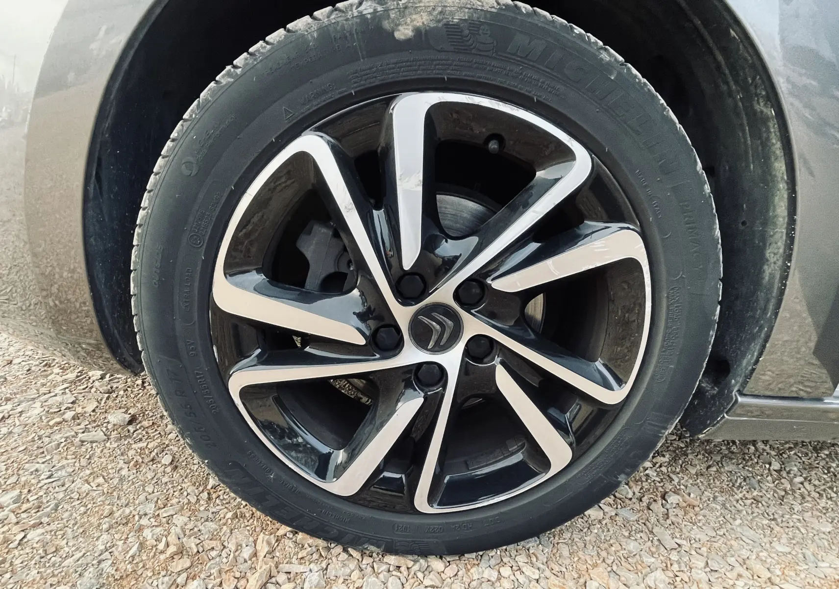 Gros plan sur la jante alliage noire et argentée d'une Citroën C4 Picasso gris métal, roue avant droite.