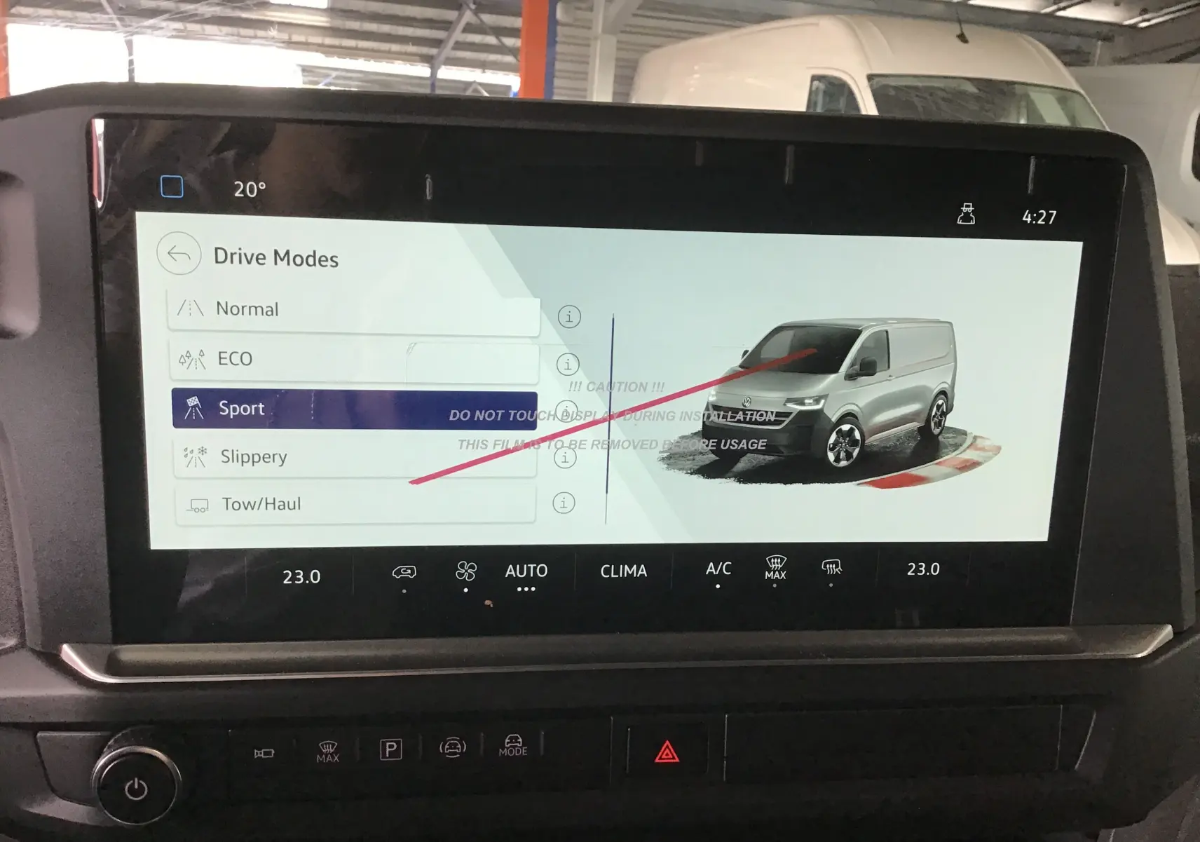 Écran tactile du tableau de bord montrant les modes de conduite avec illustration d’un Volkswagen Transporter gris anthracite en 3/4 avant.