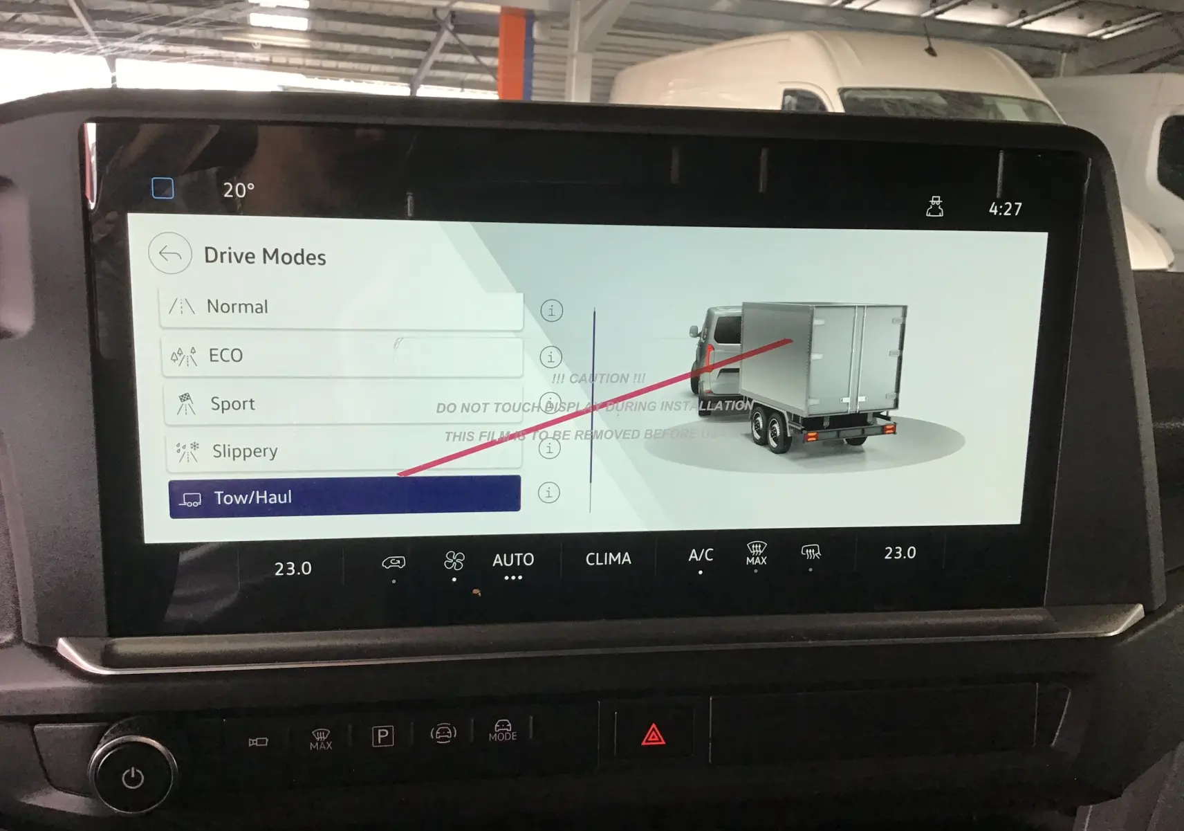 Écran tactile intérieur du Volkswagen Transporter T7 montrant les modes de conduite avec illustration d’un utilitaire gris anthracite vu de l’arrière.