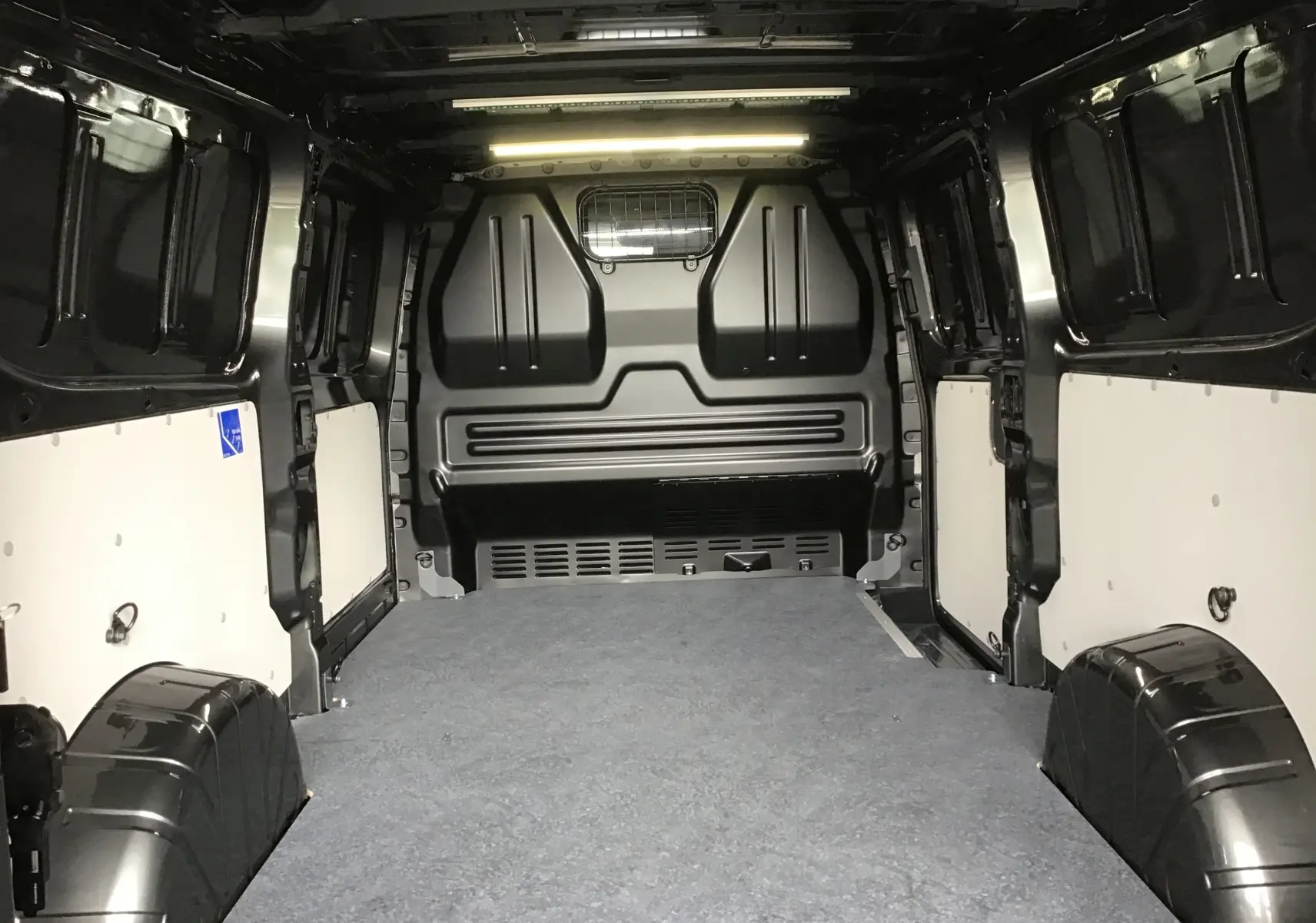 Intérieur du coffre du Volkswagen Transporter T7 gris anthracite, vue depuis l'arrière vers la cloison séparatrice.