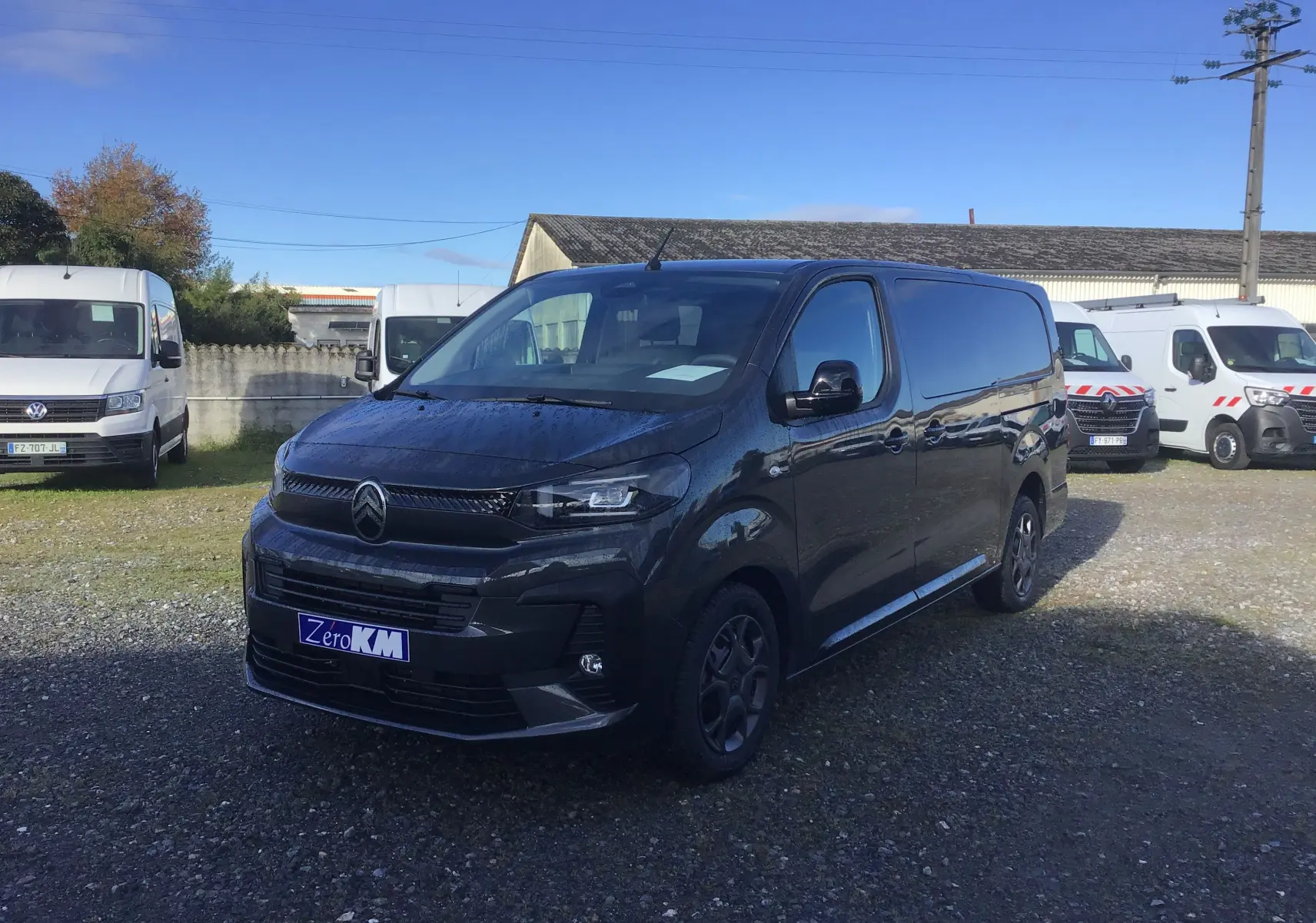 Vue 3/4 avant d'un Citroën Jumpy cabine approfondie gris titane, avec calandre noire et jantes spécifiques, stationné en extérieur.