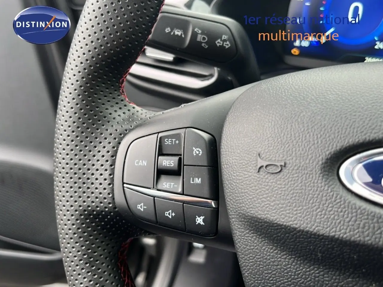 Gros plan sur le volant perforé avec commandes intégrées du Ford Puma gris Magnetic Metal, version hybride 2024.