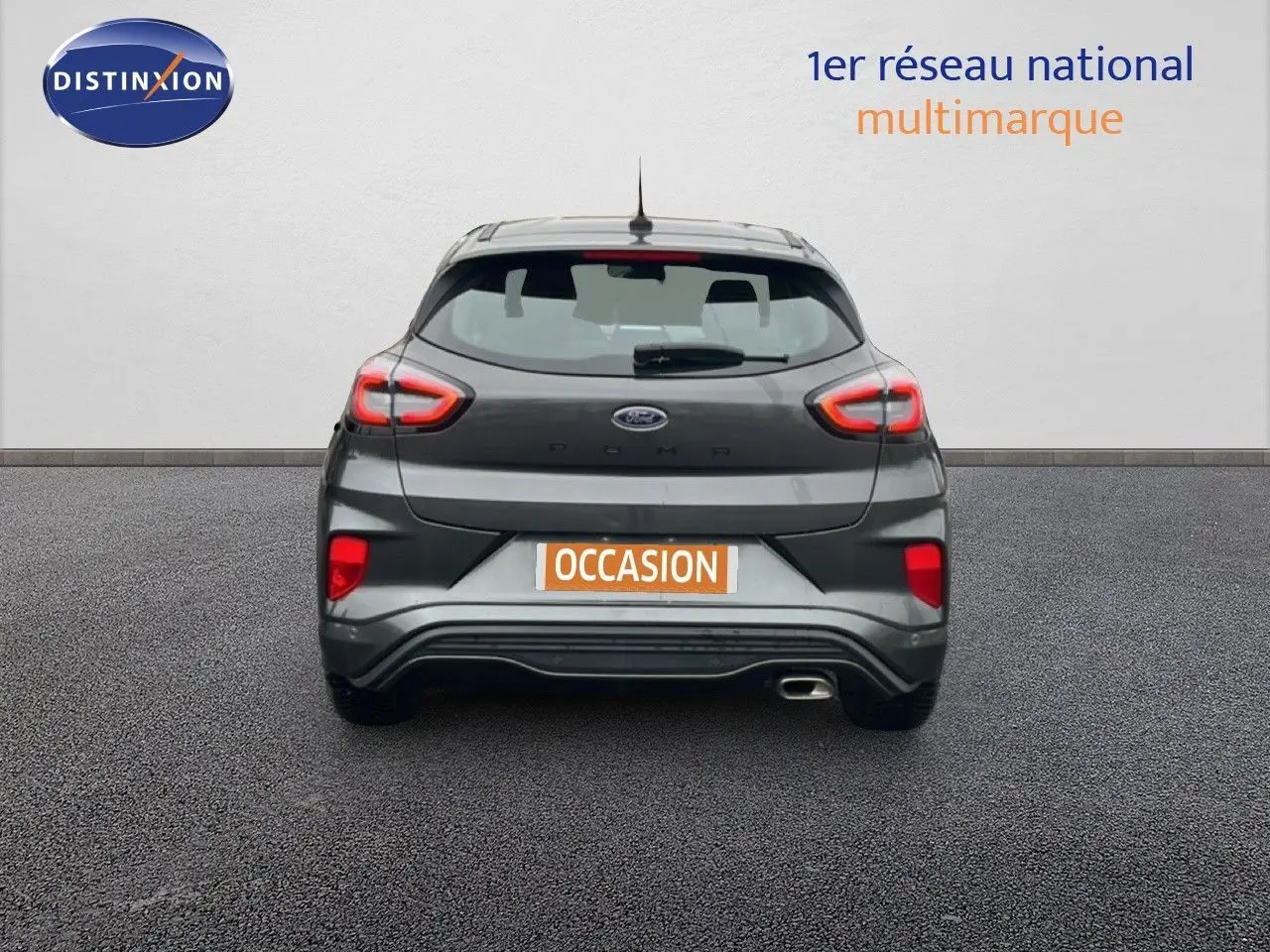 Vue arrière d'une Ford Puma gris magnetic metal 2024 avec feux LED allumés et sortie d'échappement visible côté droit.