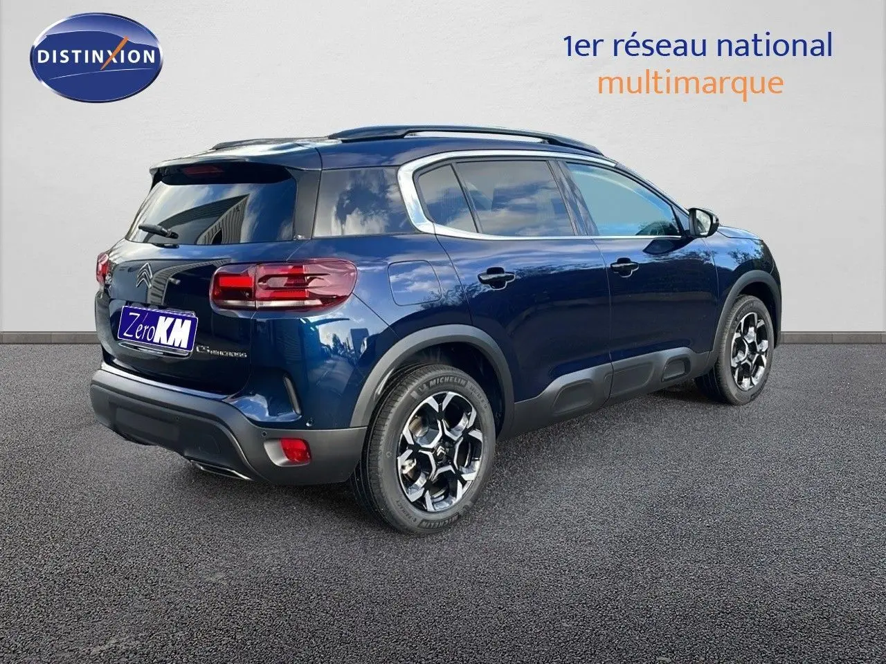 Vue 3/4 arrière droite du Citroën C5 Aircross 2025 bleu Eclipse Metal avec jantes bi-ton et barres de toit.