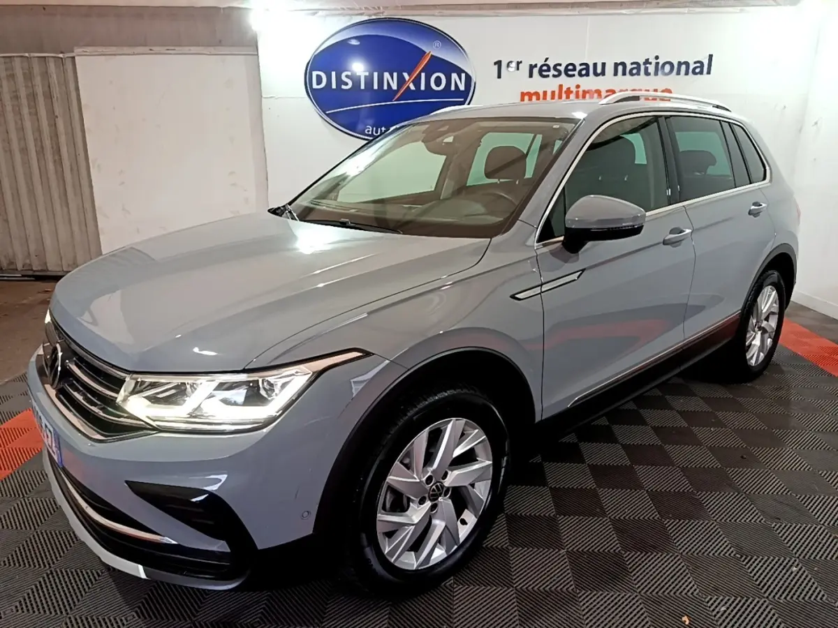 Volkswagen Tiguan gris foncé vu en 3/4 avant droit dans un showroom avec éclairage intérieur.