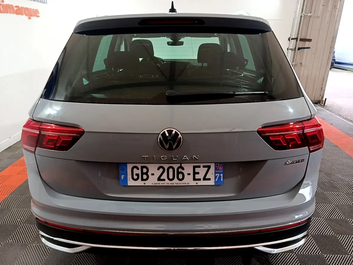 Vue arrière d'un Volkswagen Tiguan gris foncé avec feux LED et logo VW bien visibles dans un garage.