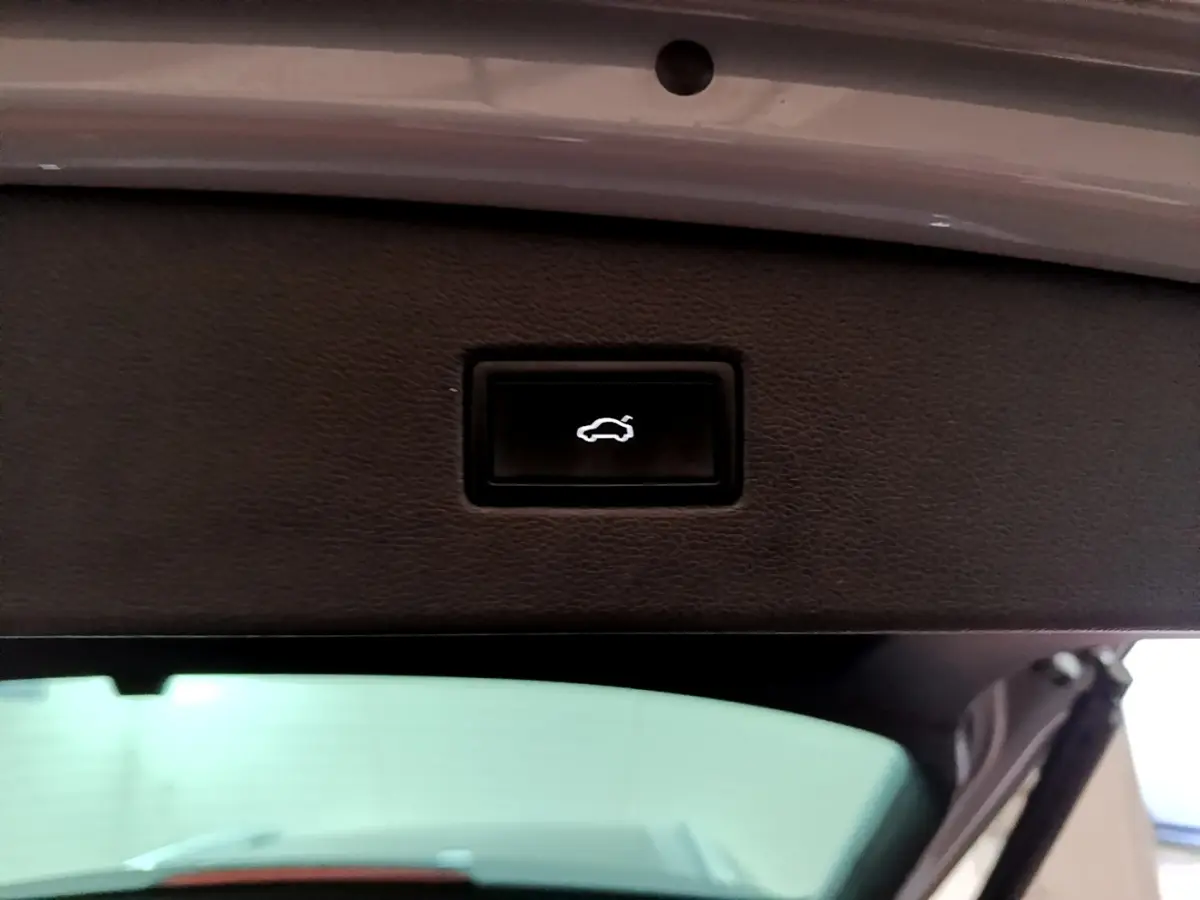 Bouton noir d'ouverture électrique du coffre sur la trappe intérieure d'un Volkswagen Tiguan gris foncé 2021.