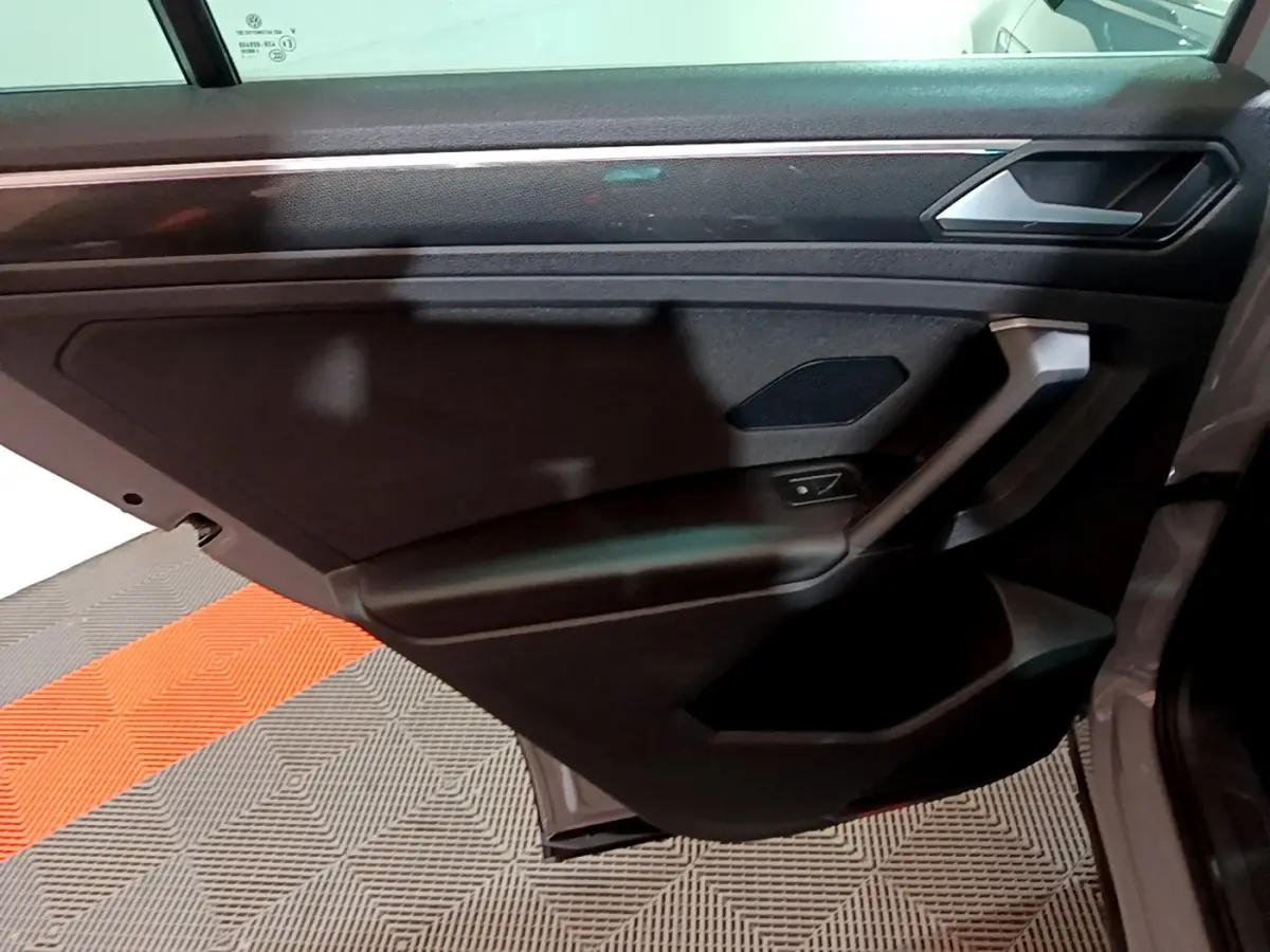 Porte arrière droite ouverte du Volkswagen Tiguan gris foncé, avec garniture intérieure noire et poignée intégrée.