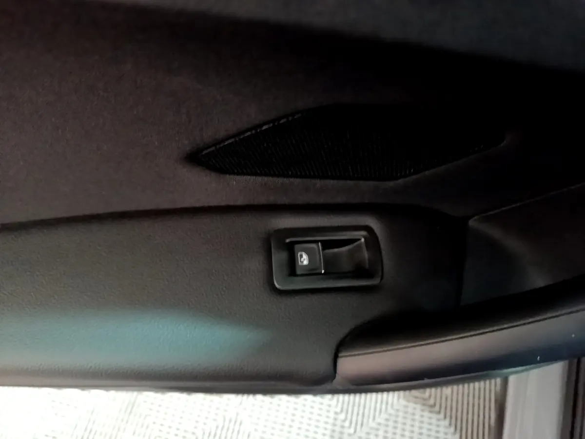 Détail du bouton d'ouverture électrique du coffre sur le panneau intérieur du hayon du Volkswagen Tiguan gris foncé 2021.