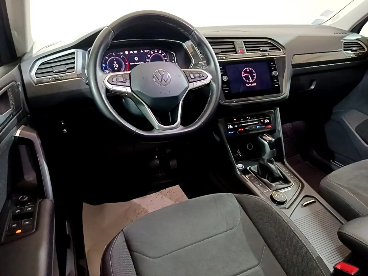 Intérieur avant du Volkswagen Tiguan gris foncé, volant cuir multifonctions et écran tactile central allumé.