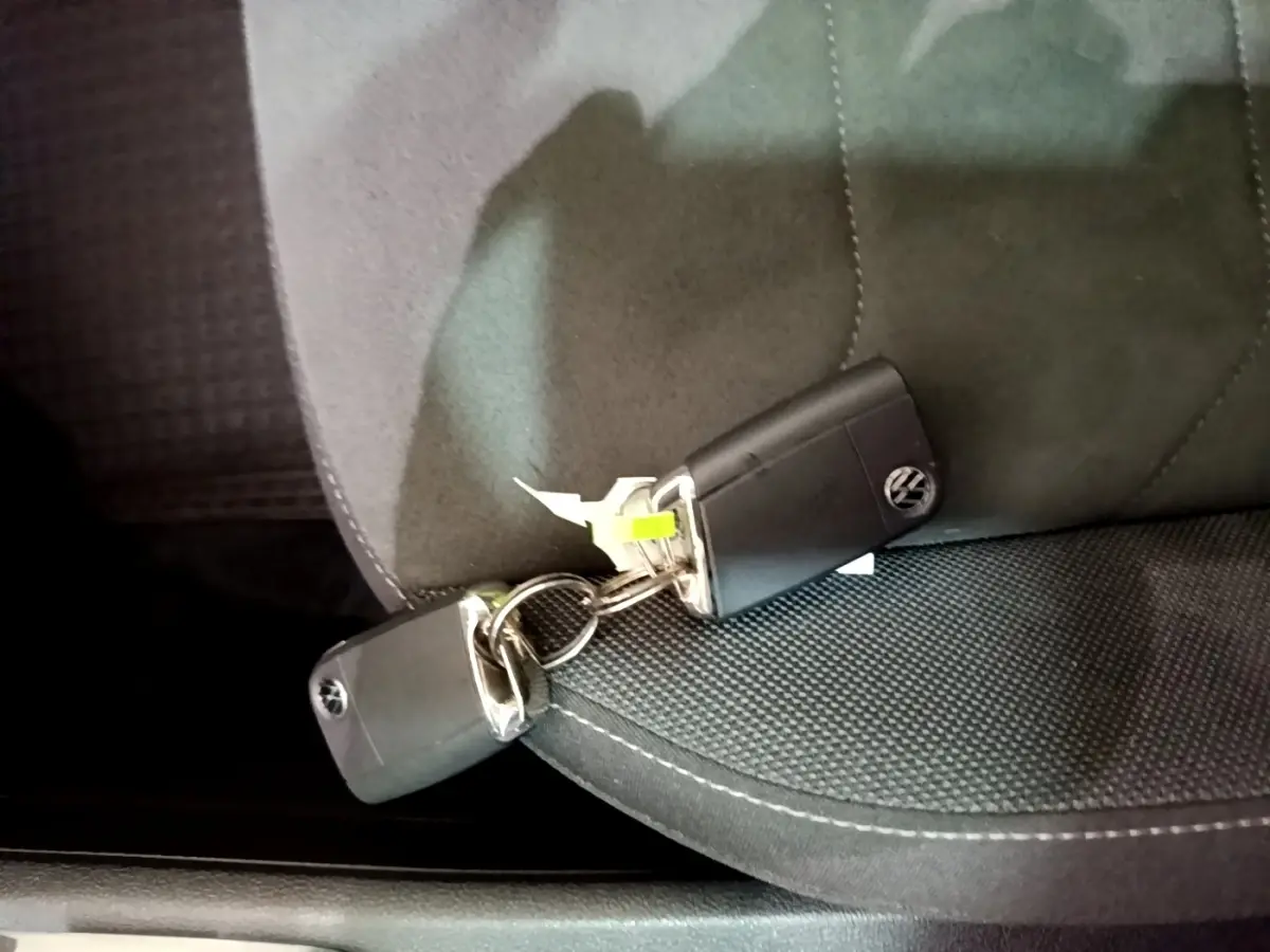 Gros plan sur deux clés Volkswagen noires posées sur un siège tissu gris foncé à surpiqûres blanches.