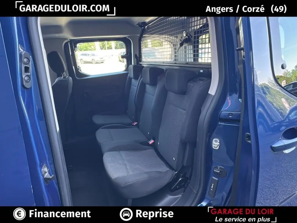 Vue intérieure côté droit sur les sièges arrière noirs du Peugeot Rifter bleu 2024 avec séparation grillagée vers le coffre.