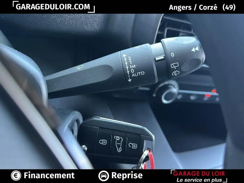 Gros plan sur la commande des essuie-glaces et la clé dans l’habitacle du Peugeot Rifter bleu 2024.