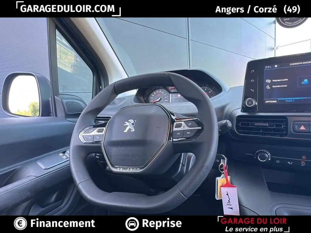 Vue intérieure centrée sur le volant Peugeot d’un Rifter bleu 2024, avec tableau de bord et écran tactile visibles.