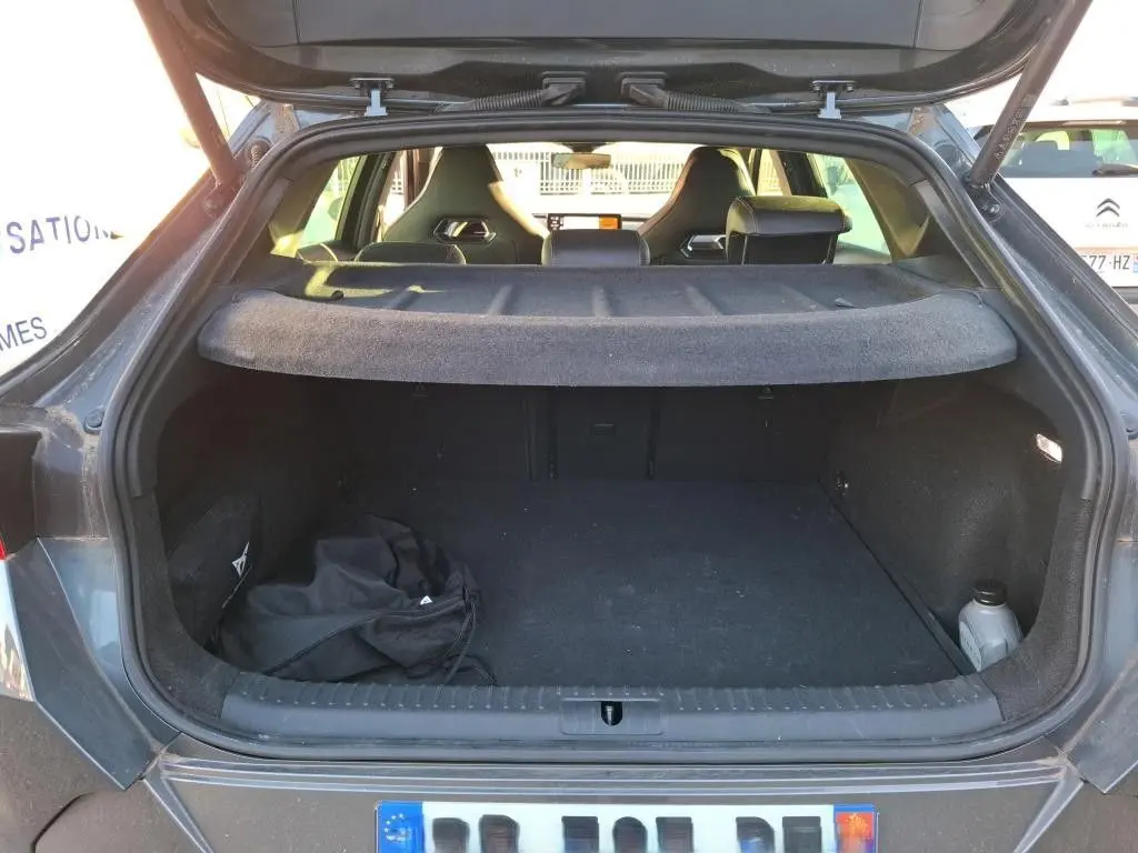 Coffre ouvert vu de l'arrière d'une CUPRA Formentor gris foncé 2023, avec cache-bagages et sièges noirs visibles.