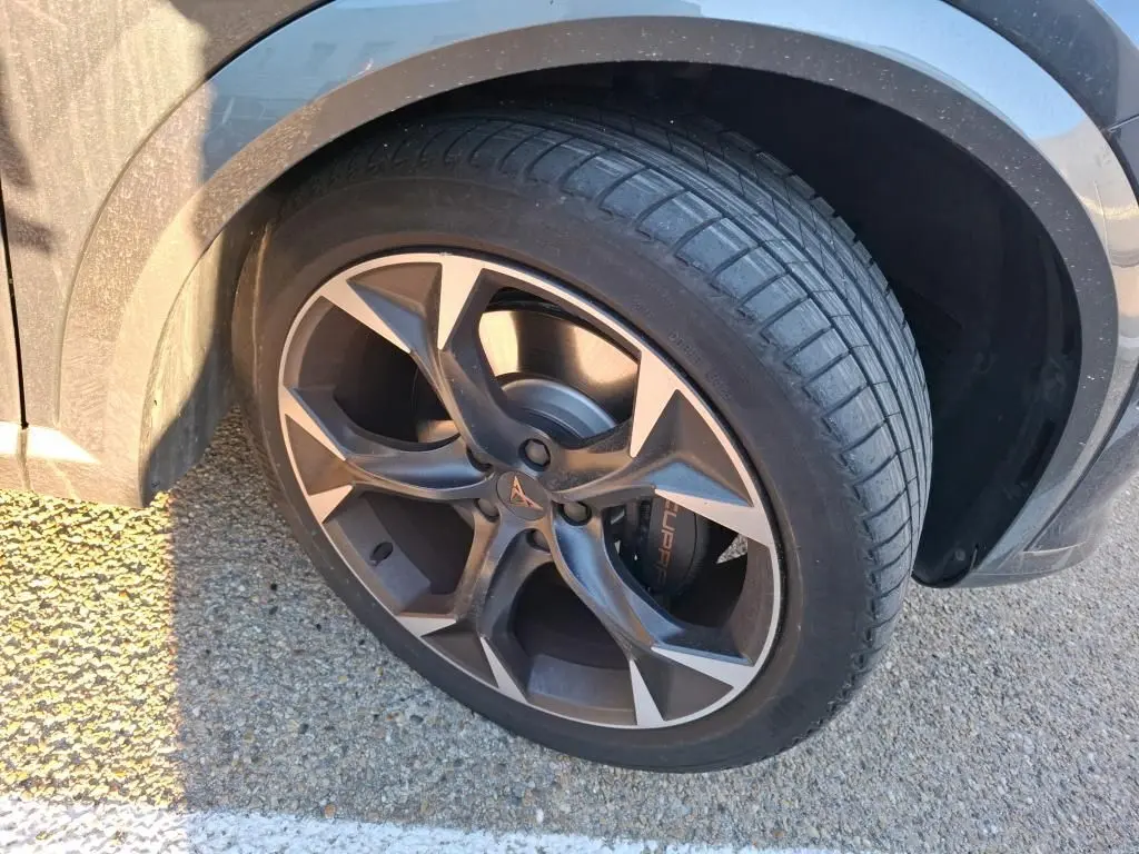 Gros plan sur la roue avant gauche gris foncé d’un CUPRA Formentor 1.4 e-HYBRID 245 DSG avec jante noire et logo CUPRA.