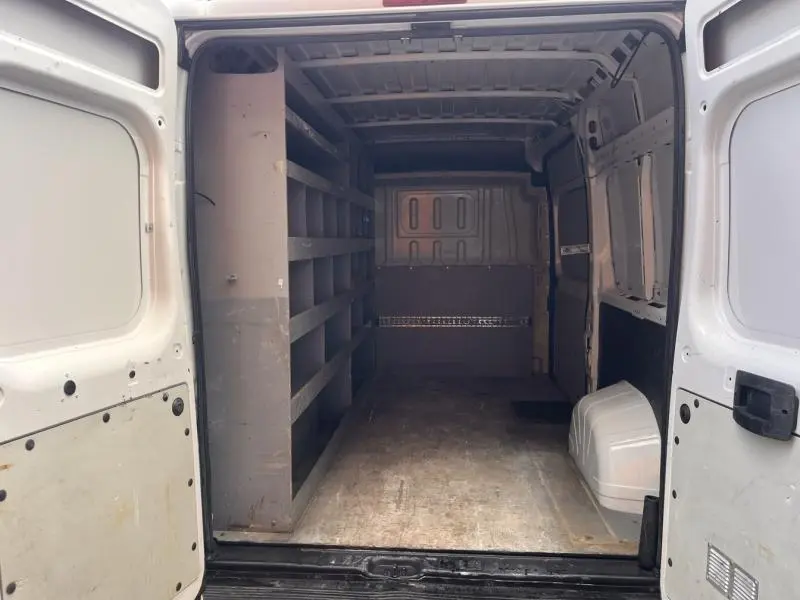 Vue intérieure arrière du Citroën Jumper blanc Icy, montrant l’espace de chargement avec étagères latérales à gauche.