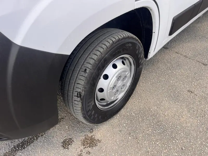 Gros plan sur la roue avant gauche du Citroën Jumper blanc Icy, avec jante acier et pare-chocs noir visible.