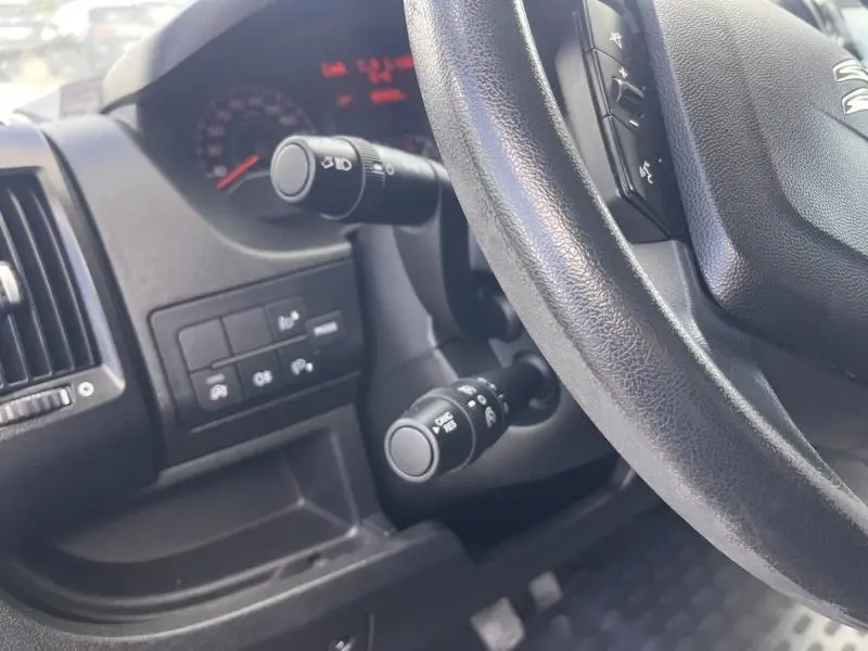 Vue rapprochée du volant multifonction et des commandes de phares du tableau de bord du Citroën Jumper blanc Icy.