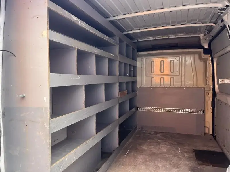 Intérieur du coffre d’un Citroën Jumper blanc Icy, vue latérale gauche montrant des étagères de rangement grises.