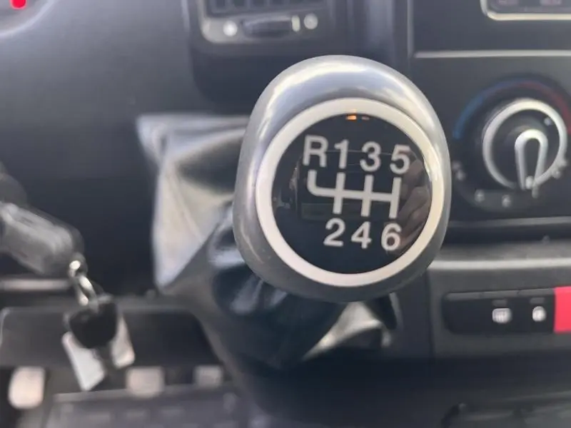 Gros plan sur le levier de vitesses manuel noir du Citroën Jumper blanc, avec indication des 6 rapports et marche arrière.