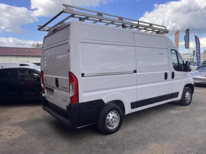 Vue 3/4 arrière droite d’un utilitaire Citroën Jumper blanc Icy avec galerie de toit et portes battantes arrière.