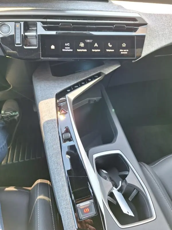 Vue intérieure du poste de conduite du Peugeot 3008 Hybrid 136 e-DCS6 Allure 2025, avec console centrale en tissu gris et écran tactile.