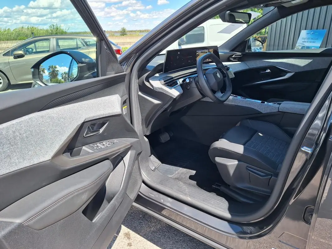 Vue intérieure côté conducteur du Peugeot 3008 Hybrid gris foncé, mettant en valeur le cockpit numérique et les finitions tissu et cuir.