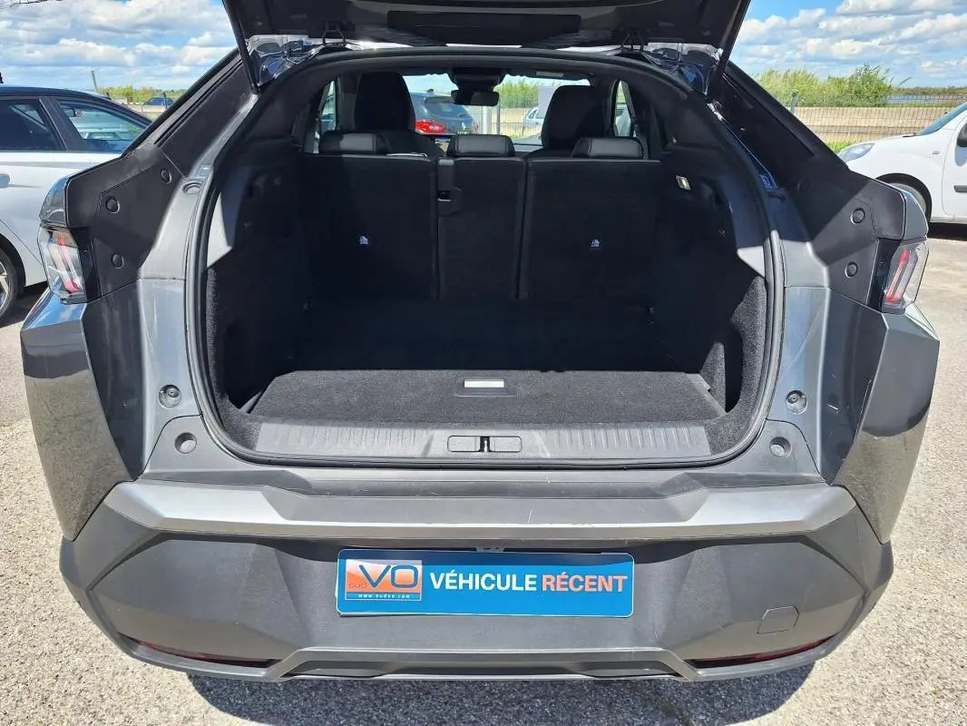 Vue arrière du coffre ouvert d’un Peugeot 3008 gris foncé, montrant l’espace de chargement et les feux arrière.
