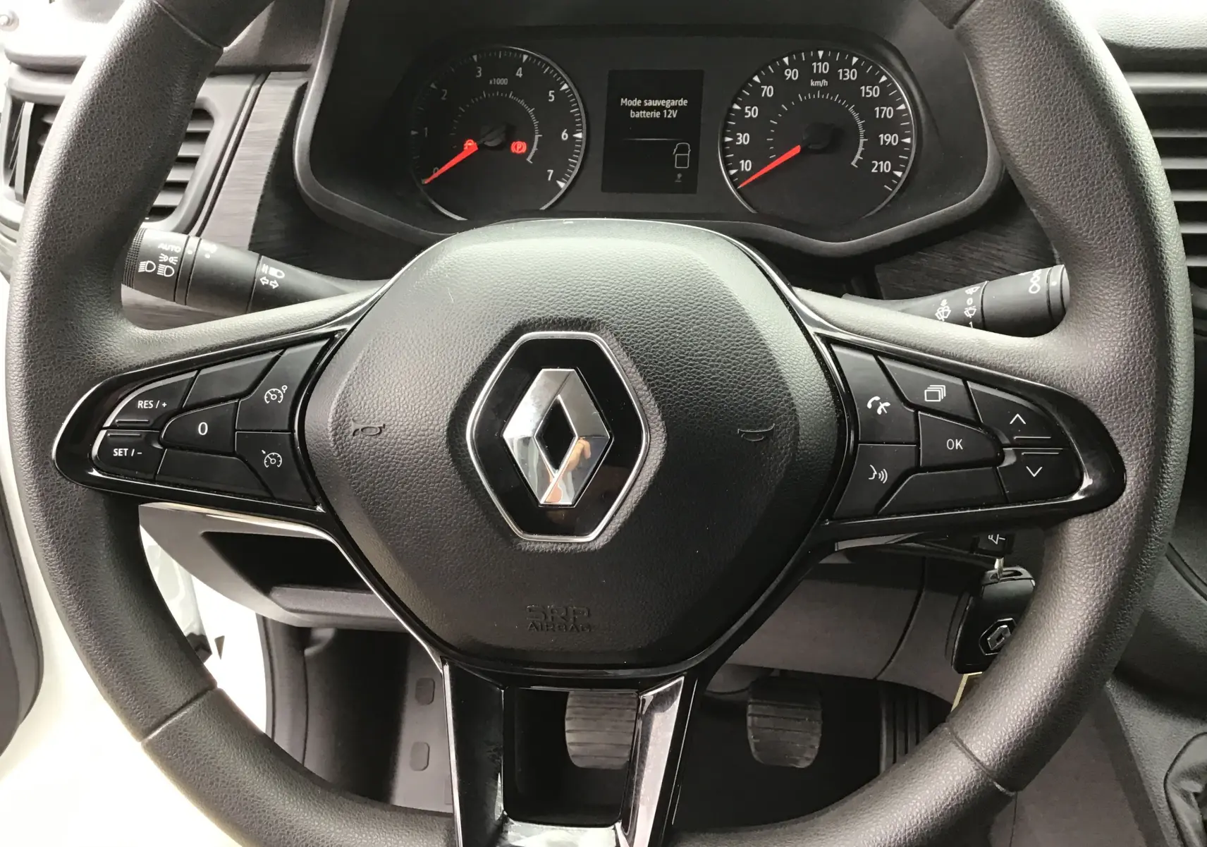 Vue rapprochée du volant noir avec logo Renault et tableau de bord du Trafic Fourgon blanc 2024.