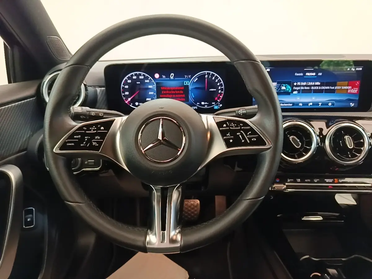 Vue intérieure centrée sur le volant cuir noir et les écrans digitaux larges du tableau de bord de la Mercedes Classe A 250 e.