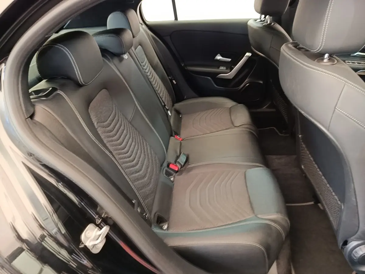 Vue intérieure côté gauche montrant la banquette arrière noire avec surpiqûres blanches de la Mercedes Classe A 250 e 2023.