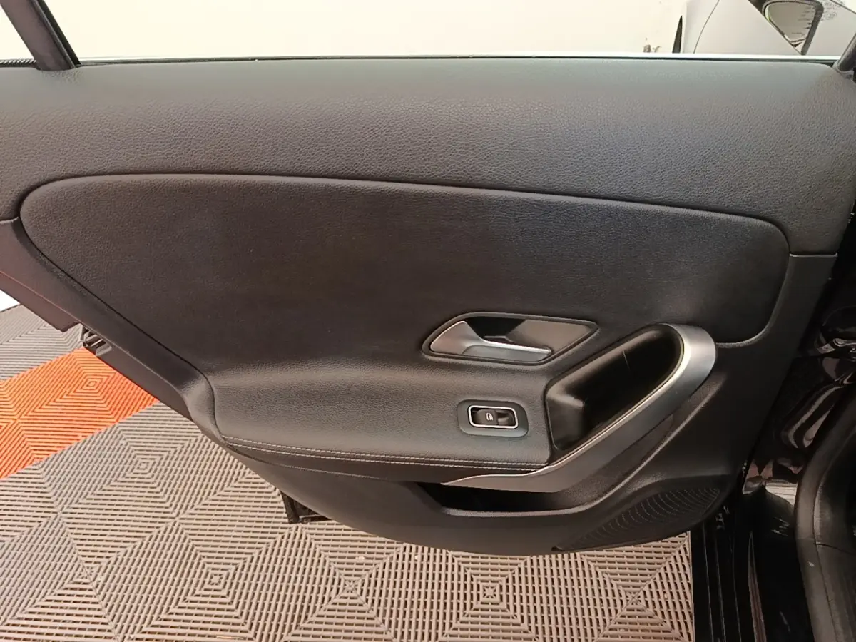 Porte intérieure côté gauche noire de la Mercedes Classe A 250 e Business Line 2023 avec poignée argentée et bouton de verrouillage.